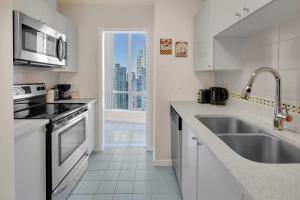 a white kitchen with a sink and a microwave at Breathtaking Downtown Condo with Stunning Harbor Views! in Vancouver