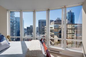 a bedroom with a large window with a view of the city at Breathtaking Downtown Condo with Stunning Harbor Views! in Vancouver