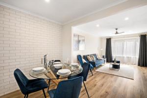 sala de estar con mesa de cristal y sillas azules en Parkview by Short & Long Stays, en Geelong