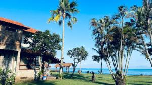 a house on the beach with palm trees and the ocean at Taverno Villa in Serang