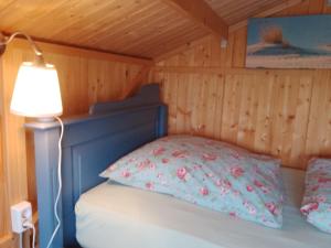a bedroom with a bed with a blue headboard and a lamp at Hütte Krötenhof, Radfahrer Übernachtung in Barförde