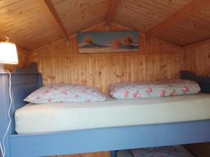 a bed in a wooden cabin with two pillows at Hütte Krötenhof, Radfahrer Übernachtung in Barförde