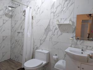 a white bathroom with a toilet and a sink at Casa Selva Viva in Tarapoto