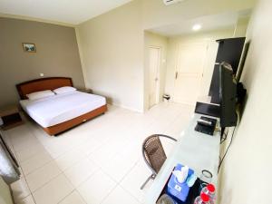 a bedroom with a bed and a desk with a television at Central City Hotel in Prabumulih