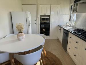 3 bed room house near airport في North Ward: مطبخ بطاولة بيضاء وثلاجة بيضاء