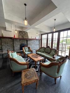 een woonkamer met banken en stoelen en een open haard bij Royal Pearl Hills (Pvt) Ltd. in Nuwara Eliya