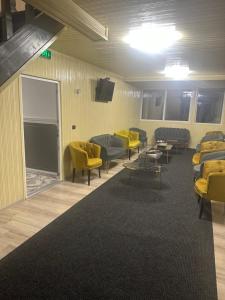 - une salle d'attente avec des canapés et des chaises jaunes dans l'établissement Pensiunea Cascada Putnei, à Lepşa