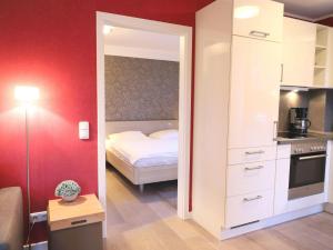 małą sypialnię z łóżkiem i kuchnią w obiekcie Miit Liebe zum Detail eingerichtete 2-Zimmer-Ferienwohnung im Zentraum von Westerland w mieście Westerland