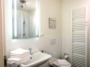 La salle de bains blanche est pourvue d'un lavabo et d'un miroir. dans l'établissement Viktoriastraße 6, Whg.7, V.-Residenz, à Westerland