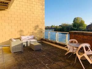 a patio with a table and chairs on a building at Stylish 2 Bed Apt with River Views & Parking - City Centre & Bay in Cardiff