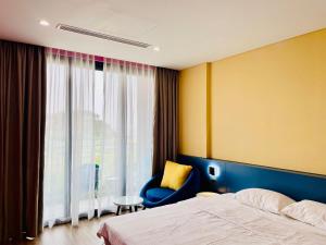 - une chambre avec un lit, une chaise et une fenêtre dans l'établissement Flamingo Ibiza Hai Tien, à Nam Khê