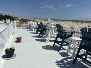 a row of chairs and tables on the beach at Oceanfront Adorable Cottage! Perfect For A Couple Or Small Family Of 4! in Ship Bottom