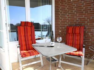 - une table et deux chaises avec une bouteille de vin sur la terrasse couverte dans l'établissement Kampstraße 3, W49, à Westerland