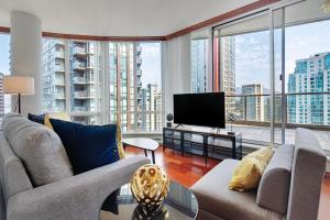 uma sala de estar com um sofá e uma televisão e janelas grandes em Designer sub-penthouse - Central Downtown Views And King Bed! em Vancouver