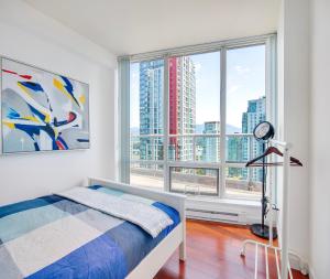 Designer sub-penthouse - Central Downtown Views And King Bed! في فانكوفر: غرفة نوم بسرير ونافذة كبيرة