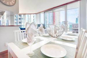 a dining room table with white plates and glasses on it at Designer sub-penthouse - Central Downtown Views And King Bed! in Vancouver