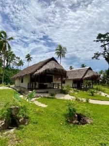 una casa con techo de hierba y palmeras en Serenity Bungalows, en Port-Olry