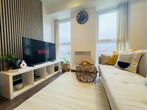 Una sala de estar con un sofá blanco y un televisor. en Central Luton Apartment, en Luton 6 fotos más