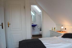 Cette chambre blanche dispose d'une salle de bains avec un lit et un lavabo. dans l'établissement Haus Carolina, Whg. 3, à Westerland