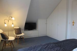 - une chambre avec un lit, deux chaises et une télévision dans l'établissement Haus Carolina, Whg. 3, à Westerland