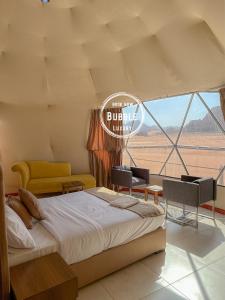 a bedroom with a bed and chairs and a window at Wadi rum Bubble luxury camp in Wadi Rum