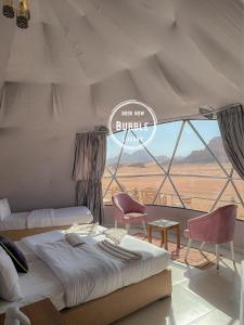 Wadi rum Bubble luxury camp في وادي رم: غرفة نوم بسرير وكرسيين ونافذة
