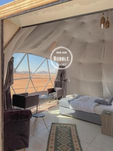 Wadi rum Bubble luxury camp في وادي رم: خيمة بسرير وعلامة مكتوب عليها العلاج بالفقاعات