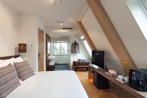 een slaapkamer met een wit bed en een televisie bij Van Heeckeren Hotel in Nes