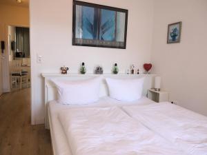 1 cama blanca con almohadas blancas en una habitación en Appartement mit 2 Balkonen, en Westerland