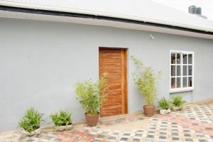 une maison blanche avec une porte en bois et des plantes en pot dans l'établissement House - King Beds - 5G Wi-Fi - Hottub -PS4, à Dar es Salaam