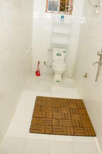 La salle de bains est pourvue de toilettes et d'un tapis en bois. dans l'établissement House - King Beds - 5G Wi-Fi - Hottub -PS4, à Dar es Salaam