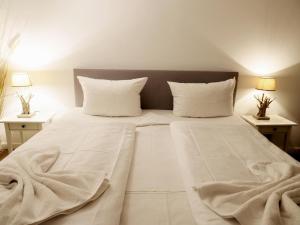een groot bed met witte lakens en kussens bij -Zimmer-Appartement über 2 Etagen in Wenningstedt in ruhiger Lage in Wenningstedt