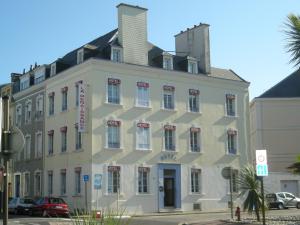 un grand bâtiment blanc au coin d'une rue dans l'établissement Hotel La Renaissance, à Cherbourg en Cotentin