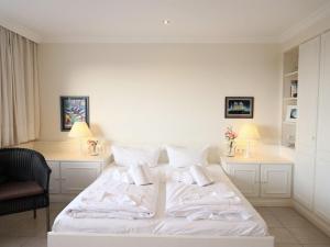 1 cama blanca en una habitación con 2 mesas en Wohnen Sie im Herzen Westerlands, in einer komplett neu renovierten 1-Zimmer Wohnung, en Westerland