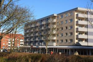 un gran edificio de apartamentos en el centro de una ciudad en Wohnen Sie im Herzen Westerlands, in einer komplett neu renovierten 1-Zimmer Wohnung, en Westerland