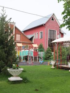 ein rotes Haus mit einem Hof mit Spielplatz in der Unterkunft Adorable 3 bedroom house villa with mountain view and beautiful garden in Baytyk