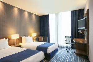 ein Hotelzimmer mit 2 Betten und einem TV in der Unterkunft Holiday Inn Express Amsterdam Arena Towers, an IHG Hotel in Amsterdam