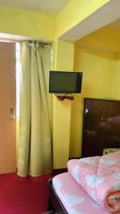 a bedroom with a bed and a flat screen tv at Dew Drops Guest House in Darjeeling