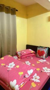 a bed with a pink bedspread with flowers on it at Dew Drops Guest House in Darjeeling
