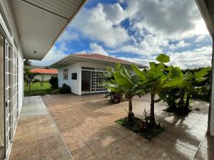 a house with a courtyard with trees in front of it at Manureva Nui Hotel Boutique in Hanga Roa