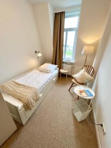ein Schlafzimmer mit einem Bett, einem Stuhl und einem Tisch in der Unterkunft Hotel Villa Klasen in Wenningstedt-Braderup