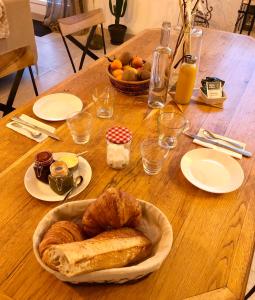 een houten tafel met een bord brood en een fruitmand bij Les chambres du Roc'h Hir à Loguivy de la Mer in Ploubazlanec