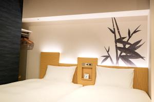 two beds in a bedroom with white sheets at Daiwa Roynet Hotel Nagoya Fushimi in Nagoya