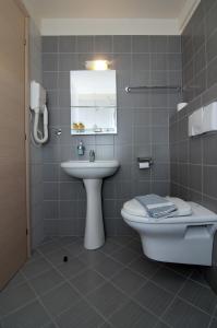 a bathroom with a sink and a toilet and a mirror at Hotel Elina in Perdika