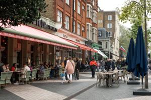 una multitud de personas caminando por una calle con mesas y sillas en Tranquil Trio Bedrooms, en Londres