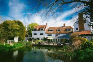 une grande maison avec un étang en face de celle-ci dans l'établissement Sheene Mill, à Melbourn