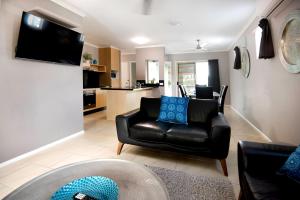 a living room with a black leather couch and a kitchen at Marlin Cove Holiday Resort in Trinity Beach