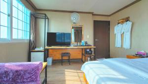 a bedroom with a bed and a desk with a television at Queen motel in Tongyeong