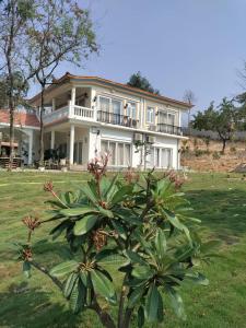 een groot wit huis met een boom ervoor bij Dezire Holidays South Goa in Goa