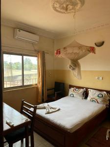 a bedroom with a bed and a table and a window at Gust Hotel in Bangui